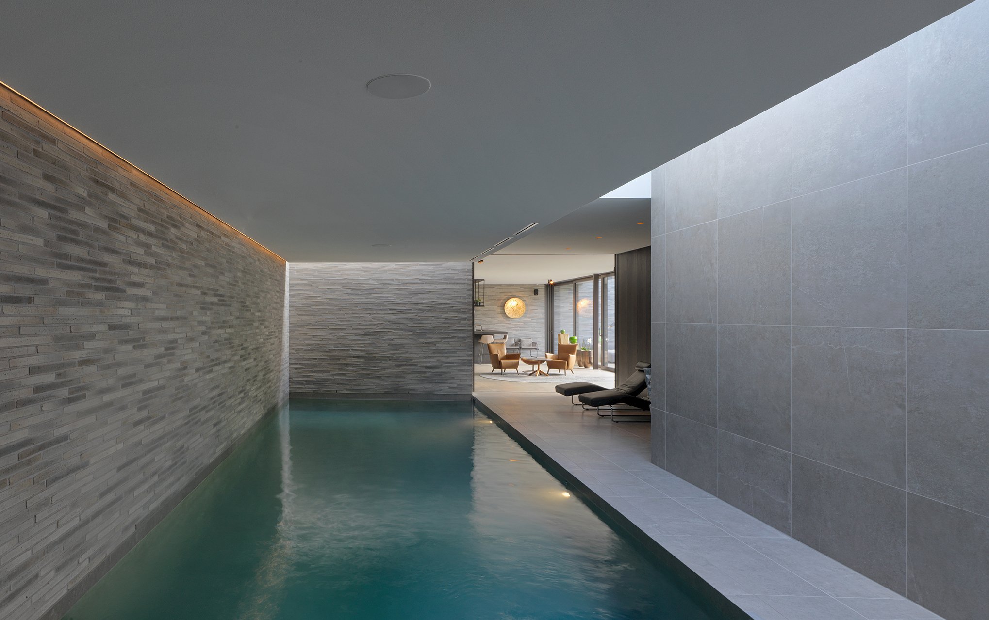 Vocht- en chloorbestendig naadloos akoestisch plafond in een luxe binnenzwembad, waarbij galm wordt geëlimineerd ondanks de harde tegelwanden en het wateroppervlak.