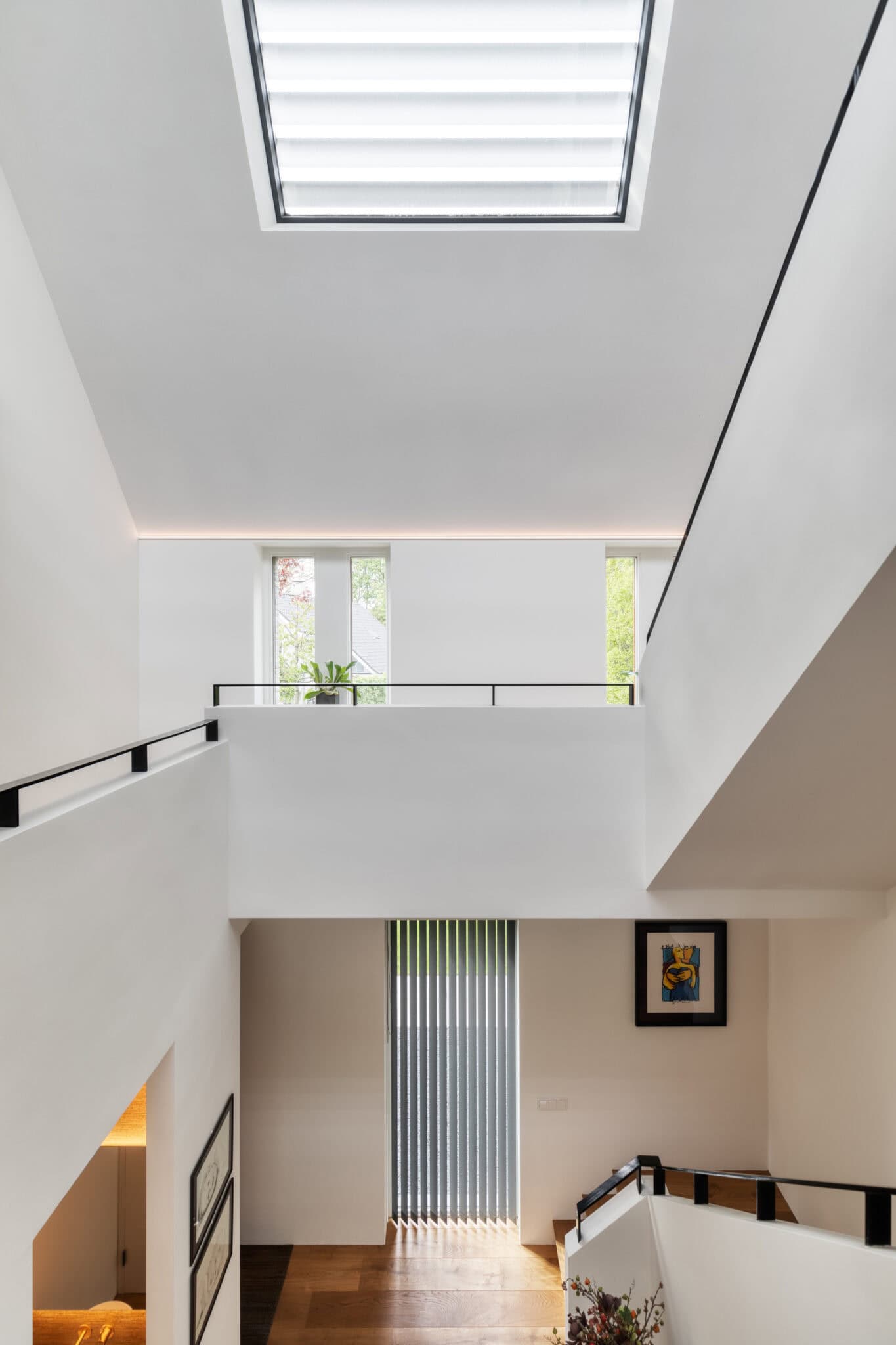 Modern woonhuis interieur met een hoge vide en een naadloos wit akoestisch plafond van Pennings voor een betere akoestiek.